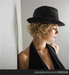 Profile of Caucasian young adult woman wearing fedora hat with eyes closed.