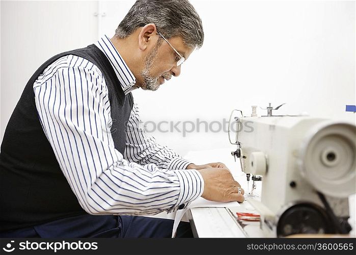 Profile of middle aged tailor using sewing machine