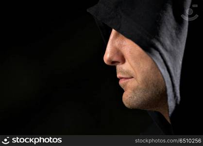 Profile of the man in a hood on a black background . Secret