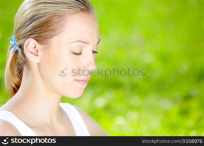 Profile of the meditating blonde against a summer landscape