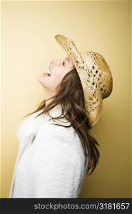 Profile of young adult Caucasian woman wearing cowboy hat leaning backwards laughing.