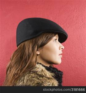 Profile of young brunette adult Caucasian woman wearing flat hat.
