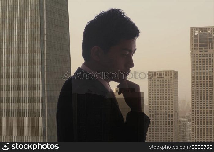 Profile of young businessman contemplating, double exposure of cityscape, Beijing