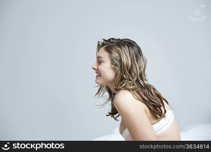 Profile of young woman in underwear, smiling on bed, close-up