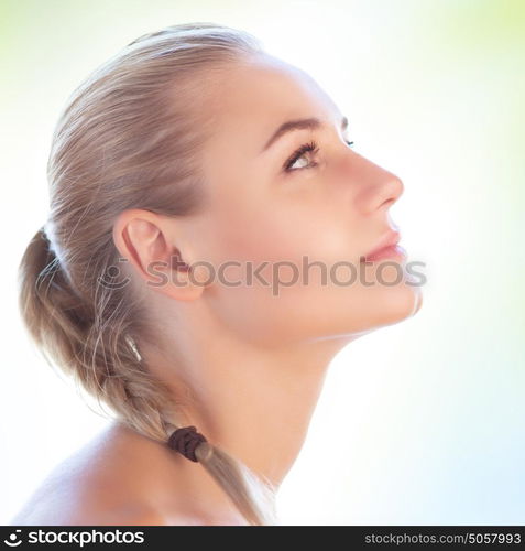 Profile portrait of a beautiful blond girl with pigtail hairstyle isolated on clear background, perfect clean skin, natural makeup, authentic beauty