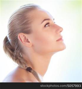 Profile portrait of a beautiful blond girl with pigtail hairstyle isolated on clear background, perfect clean skin, natural makeup, authentic beauty