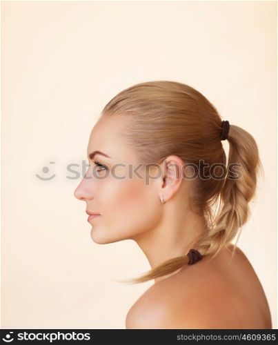 Profile portrait of a beautiful sensual woman with braid hairstyle over beige background, gentle natural makeup, natural beauty of a woman face with a healthy skin, copy space