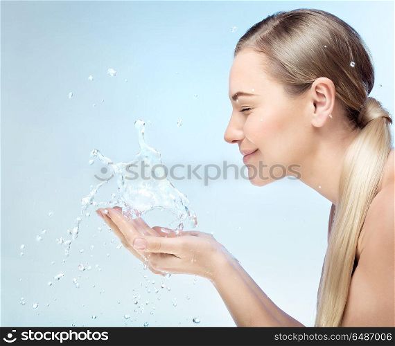Profile portrait of a nice blond girl with pleasure washing her face in the morning by clear refreshing water, perfect clean skin, using anti acne remedy, hygiene concept. Morning freshness concept