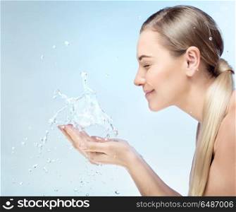 Profile portrait of a nice blond girl with pleasure washing her face in the morning by clear refreshing water, perfect clean skin, using anti acne remedy, hygiene concept. Morning freshness concept