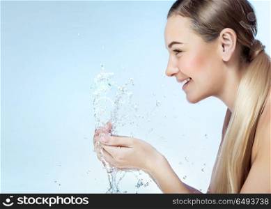 Profile portrait of a nice blond girl with pleasure washing her face in the morning by clear refreshing water, perfect clean skin, using anti acne remedy, photo with a copy space. Fresh face