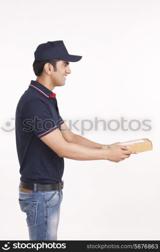 Profile shot of delivery man giving package against white background