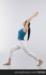 Profile shot of young woman doing back bend yoga pose on wooden floor