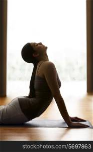 Profile shot of young woman doing yogic &rsquo;sun salutation&rsquo; on mat