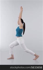 Profile shot of young woman stretching arms upwards isolated over gray background