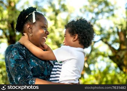 Profile view of an happy african mother hugging her little child in nature