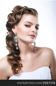 Profile view of beautiful bride dressed in white dress. Festive coiffure and makeup