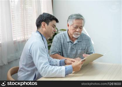 Profile view of caucasian cardiologist consulting doctor with his senior elder asian patient with help of document file during checkup and how to take medicine at home.Selective focus on elder patient