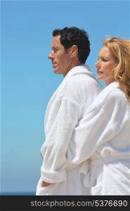 Profile view of couple by the sea wearing bathrobes
