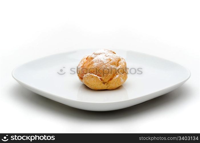 Profiterole. Single profiterole on a plate, isolated, white background