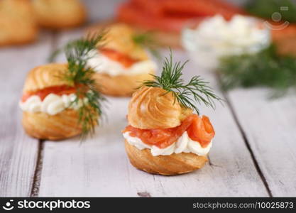 Profiteroles stuffed with cream cheese and salmon, decorated with a sprig of dill. Close-up 