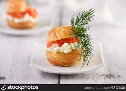 Profiteroles stuffed with cream cheese and salmon, decorated with a sprig of dill. Close-up