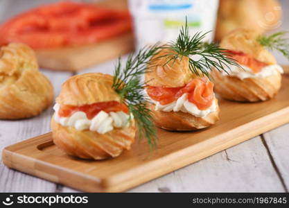 Profiteroles stuffed with cream cheese and salmon, decorated with a sprig of dill. Close-up