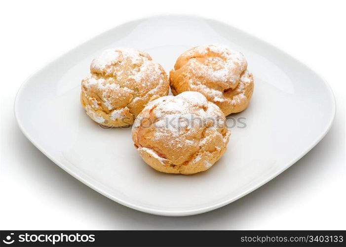 Profiteroles. Three profiteroles on a plate, isolated, white background