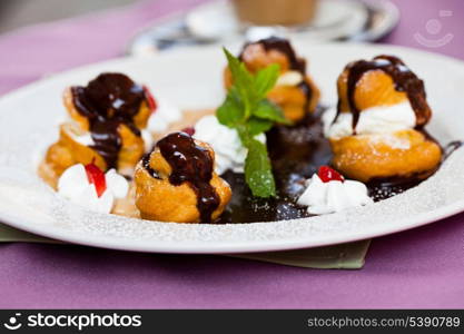 Profiteroles with ice cream and chocolate on plate