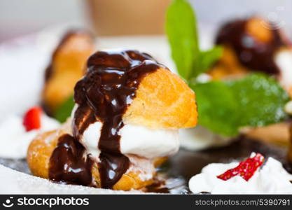 Profiteroles with ice cream and chocolate on plate