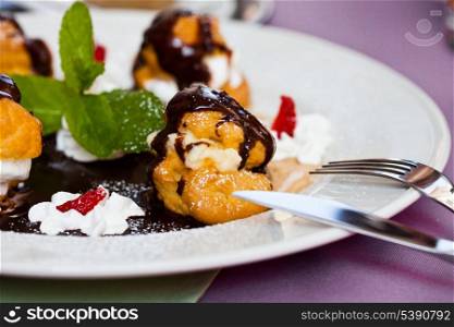 Profiteroles with ice cream and chocolate on plate