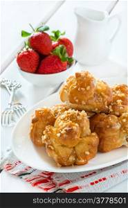 Profiteroles with nuts and strawberries over light background