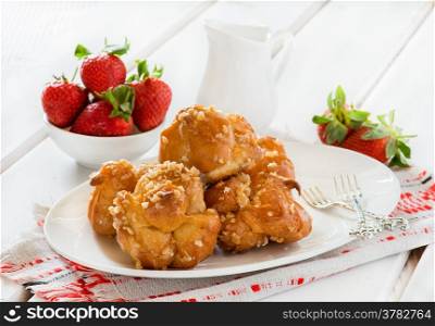 Profiteroles with nuts and strawberries over light background