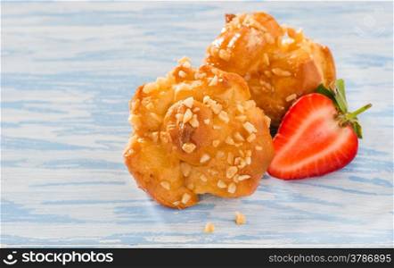 Profiteroles with nuts over light blue background, selective focus
