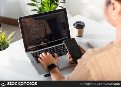 Programmer woman looking mobile phone program code at workplace, software developer hands typing data coding programming javascript with laptop computer, IT startup concept, Web application design