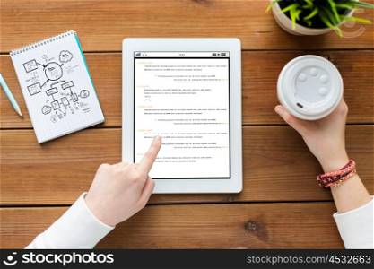 programming, business, education, technology and people concept - close up of woman with coding on tablet pc computer screen and coffee on wooden table