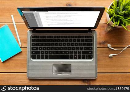 programming, education, business and technology concept - close up of laptop computer with coding on screen on wooden table