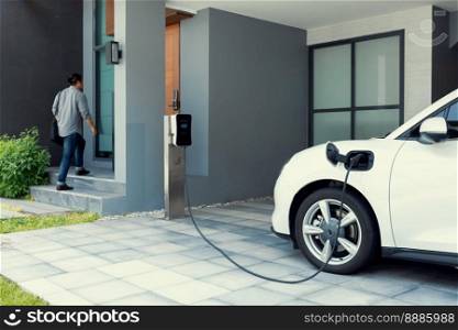 Progressive asian man and electric car with home charging station. Concept of the use of electric vehicles in a progressive lifestyle contributes to a clean and healthy environment.. Progressive concept of asian man and electric car with home charging station.