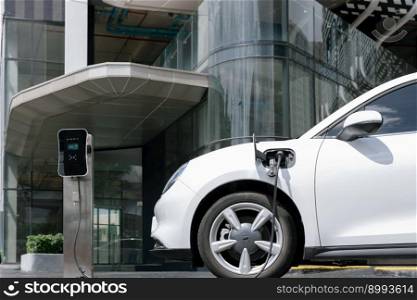 Progressive electric vehicle recharging battery at charging station powered by sustainable clean energy at city residential area. Eco-friendly vehicle concept.. Progressive EV car at city residential with electric charging station.