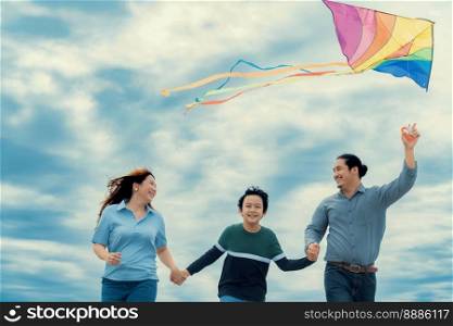 Progressive happy family vacation and carefree day concept. Young parents mother father and son run along and flying kite together road with enjoy natural scenic on scenery and clear sky background.. Progressive happy family vacation concept with outdoor flying kite on the road
