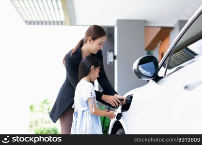 Progressive lifestyle of mother and daughter who have just returned from school in an electric vehicle that is being charged at home. Electric vehicle powered by sustainable clean energy.. Progressive lifestyle of mother and daughter with EV car and charging station.