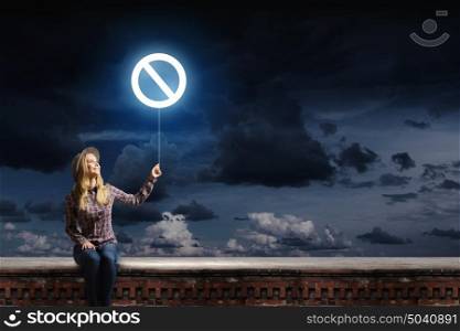 Prohibition concept. Young woman in casual holding balloon with prohibition sign