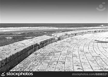Promenade along the Mediterranean Sea in Akko. Embankment and city beach of old arabic city Akko, located north of Israel. Black and white picture