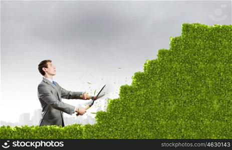 Promotion concept. Young businessman cutting bush in shape of ladder