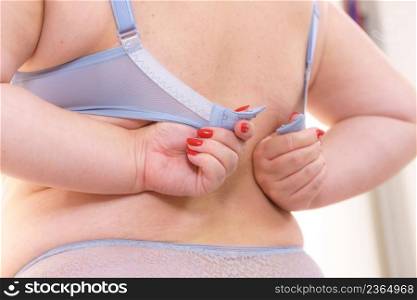 Proper fitting bras. Big woman opening taking off or putting on her bra. Plus size overweight female wearing lingerie, back view.. Woman wearing bra. Back view