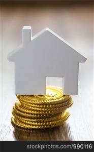 Property Concept With Model Houses On Pile Of Gold Coins