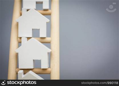 Property Ladder Concept With Model Houses On Wooden Ladder