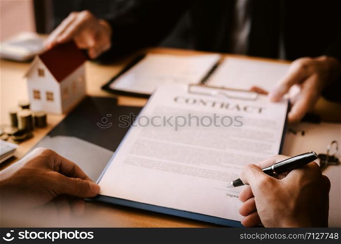 Property sales staff submit land mortgage contract documents to home buyers for sign.