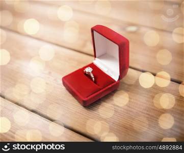 proposal, engagement, valentines day and holidays concept - close up of red gift box with diamond engagement ring on wood (vintage effect)