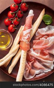 prosciutto ham and grissini bread sticks. italian antipasto