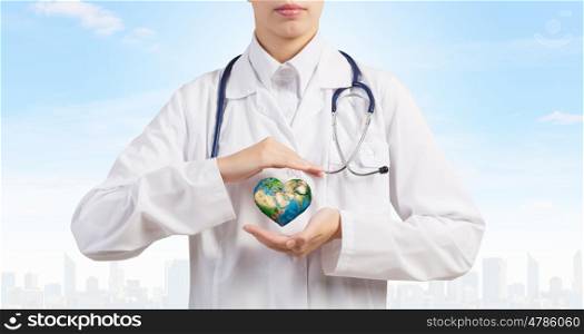 Protect Earth. Close up of female doctor holding heart in hands. Elements of this image are furnished by NASA